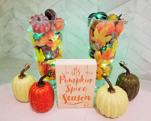 Make this glowing Fall decorations with two glass vases, fake pumpkins, twinkle lights and a fall sign with items from Dollar tree. A cheap and cute fall decorations for Halloween and Thanksgiving season.