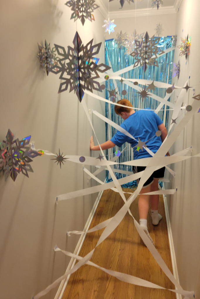 Create a fun indoor obstacle course for winter with kids racing through an ice hallway maze. Use streamers and swowflakes to create the winter wonderland an easy snow day or rainy day activity when you're stuck indoors this winter. It's also a really fun Frozen Birthday Party game. Kids will love trying to get through the icy laser maze without knocking down the icicles. Find out how easy it is to make!